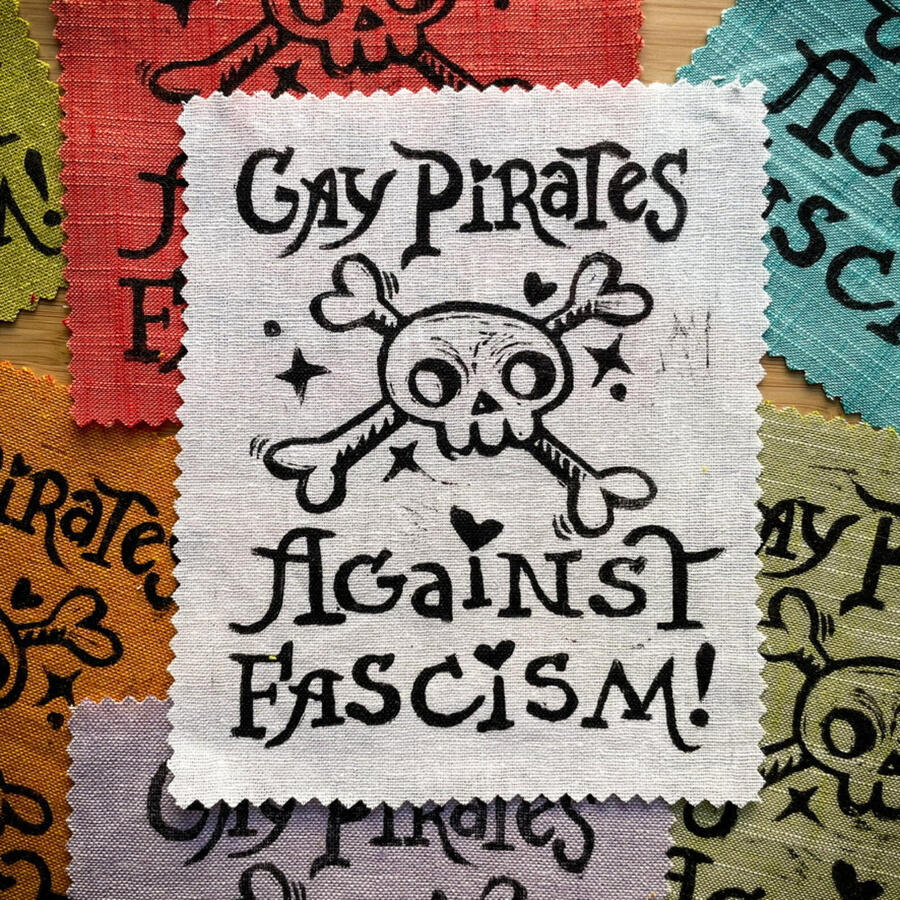 Block printed patches that read "Gay Pirates Against Fascism" with a skull and crossbones and hearts
